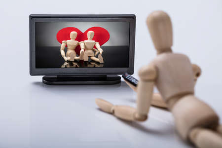 Wooden Figure Lying On Floor Watching Television