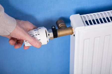 Close-up Of A Person's Hand Adjusting Temperature Of Radiator Thermostat
