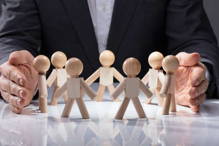 Human Hand Protecting Wooden Figures On White Backgroundの写真素材