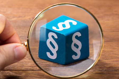 Close-up Of A Person Examining The Blue Paragraph Block With Magnifying Glass