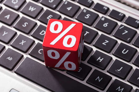 Close-up Of Percentage On The Red Wooden Block Over The Laptop Keypad