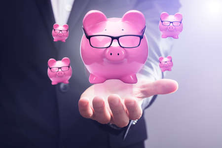 Close-up Of A Pink Piggy Banks Floating In Mid-air Over Businessperson's Handの写真素材
