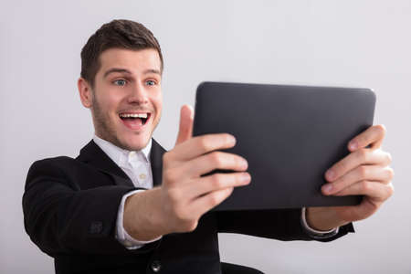 Close-up Of A Happy Young Businessman Looking At Digital Tabletの写真素材