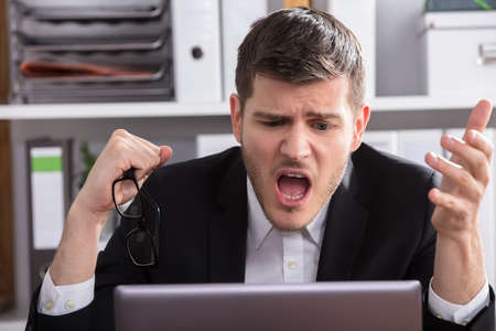 Close-up Of A Shocked Young Businessman Looking At Laptopの写真素材