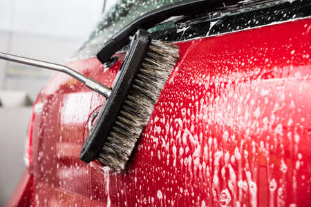 Close-up Of Person's Hand Washing Car Using Broomの写真素材
