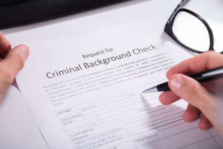 Close-up Of Person Hand Filling Criminal Background Check Application Formの写真素材