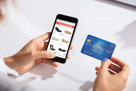 Close-up Of A Woman Holding Credit Card In Hand Doing Online Shopping Using Smart Phone