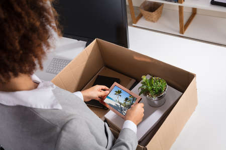 Close-up Of A Businesswoman Packing Picture Frame In Cardboard Box At Workplace