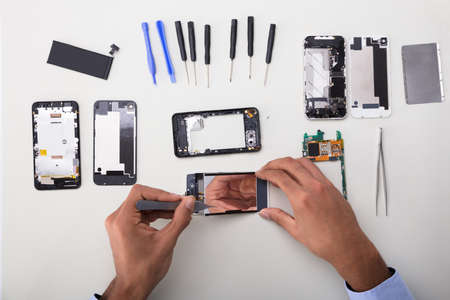 Close-up Of A Technician's Hand Fixing Damaged Screen On Mobile Phoneの写真素材