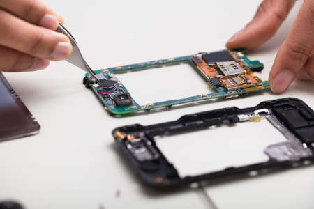 Close-up Of A Technician's Hand Repairing Damaged Smartphone