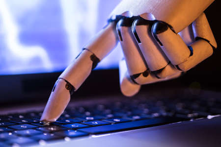 Close-up Of A Robot's Hand Typing On Laptopの写真素材