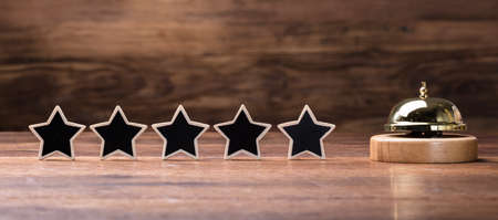 Black Five Stars Shape Arranged In Row With Service Bell On Wooden Table