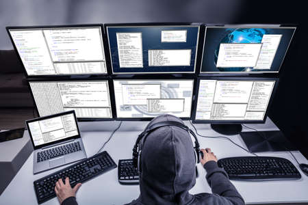 High Angle View Of A Hacker Stealing Information From Multiple Computers In Office