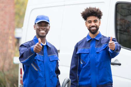 Portrait Of Two Happy Male Janitor Standing Against Truck Giving Thumbs Upの写真素材