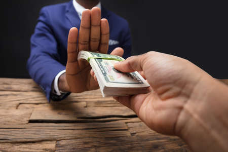 Close-up Of Businessman's Hand Refusing To Take Bribe From Partnerの写真素材