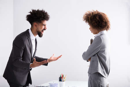 Angry Young Businessman Shouting At Female Executive In Officeの写真素材
