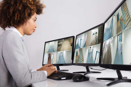 Businesswoman Looking At Multiple Camera Footage In Office