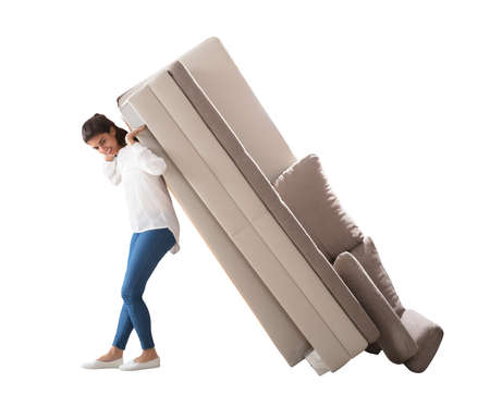 Side View Of A Happy Young Woman Lifting Sofa On White Backgroundの写真素材