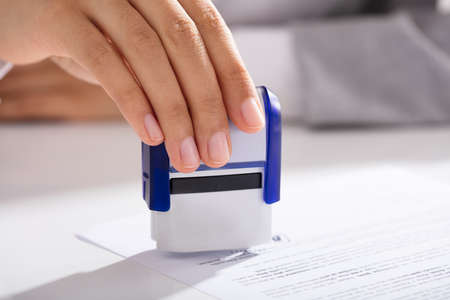 Close-up Of Person's Hand Approving Contract Form