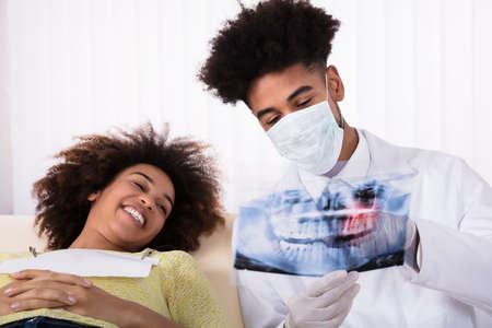 Male Dentist Showing Teeth X-ray To Happy Female Patient In Clinicの写真素材