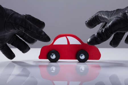 Close-up Of A Thief's Hand Wearing Gloves Stealing Red Carの写真素材