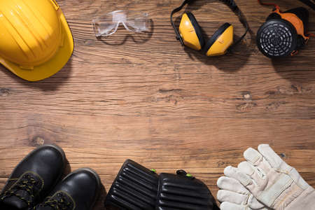 Close-up Of Yellow Hard Hat With Safety Equipment On Wooden Backgroundの写真素材
