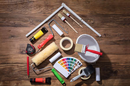 Elevated View Of House Made With Painting Equipments And Measuring Tape On The Wooden Tableの写真素材