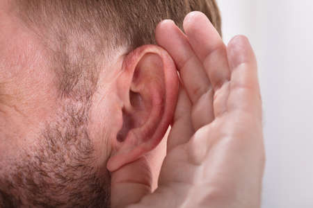Close-up Of A Man Trying To Hear With Hand Over Earの写真素材