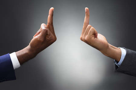 Two Businesspeople Showing Fuck Off With The Middle Finger Against Gray Background