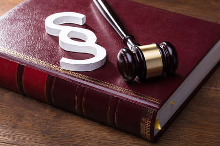 Close-up Of Big White Paragraph Symbol, Mallet And Law Book On Wooden Tableの写真素材
