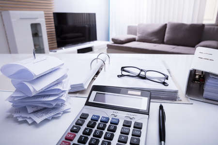 Close-up Of Folders With Receipts And Calculator On White Desk In Bedroomの写真素材