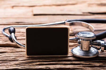 Close-up Of Blank Slate And Stethoscope On Wooden Backgroundの写真素材