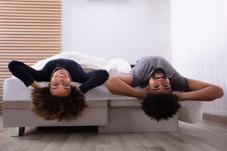 Happy Young Couple Lying On Bed In Bedroom