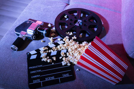 High Angle View Of Spilled Popcorn With Clapperboard And Movie Camera At Nightの写真素材