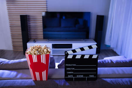 Close-up Of Clapperboard And Popcorn In Front Of Televisionの写真素材