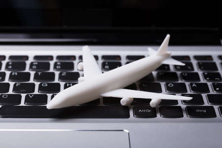 Elevated View Of White Airplane Miniature On Laptop Keypad