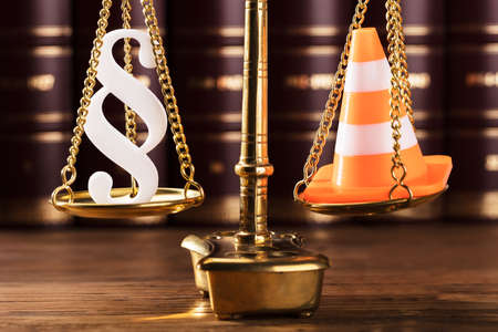 Close-up Of White Paragraph Symbol And Traffic Cone On Justice Scale In Courtroomの写真素材