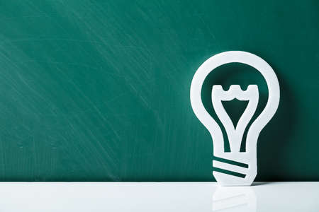 Close-up Of A White Lightbulb Leaning On Green Chalkboardの写真素材