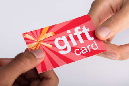 Close-up Of Two Businesspeople Hand Holding Red Gift Card