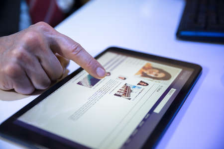 Close-up Of A Businessperson's Hand Using Social Networking Site On Digital Tablet