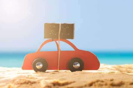 Close-up Of A Red Car With Luggage On Sandy Beach During Sunny Dayの写真素材
