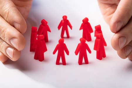 Close-up Of A Human Hand Protecting Red Human Figures On White Backgroundの写真素材