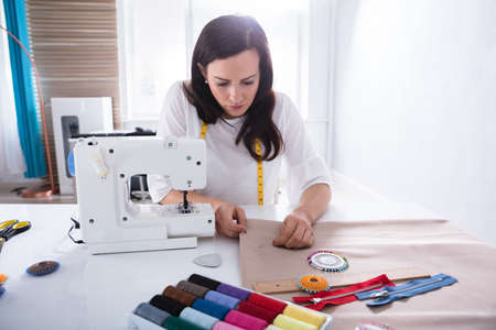 Young Female Fashion Designer Sewing Fabric With Needle In Studioの写真素材