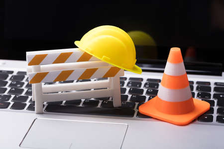 Road Barrier With Hard Hat And Traffic Cone On Laptop Keypadの写真素材