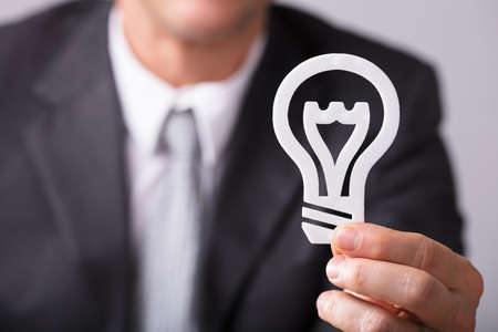 Close-up Of A Businessperson's Hand Holding White Lightbulbの写真素材