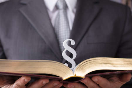 Close-up Of A Judge's Hand Holding Law Book With Paragraph Symbolの写真素材