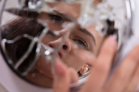 Reflection Of A Woman's Face In Broken Mirrorの写真素材