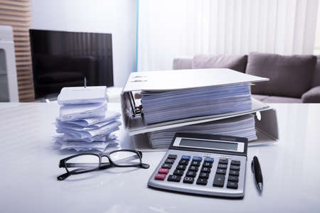 Close-up Of Folders With Receipts And Calculator On White Desk In Bedroom