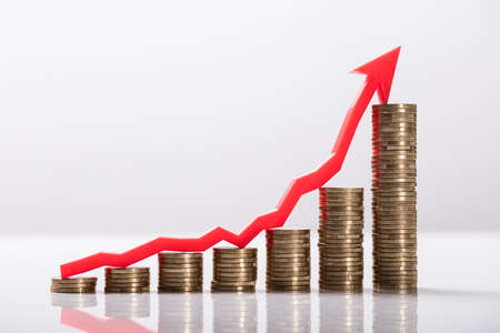 Close-up Of Increasing Golden Coins With Red Arrow Showing Upward Directionの写真素材