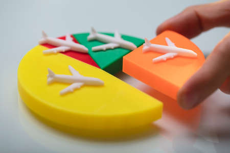 Person Arranging The Last Orange Piece Into Colorful Pie Chart With Miniature Airplaneの写真素材